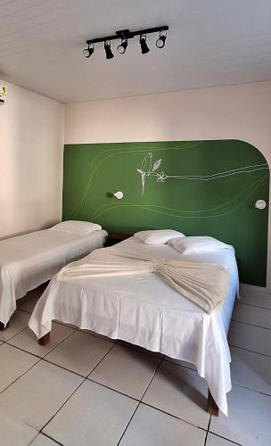 two beds in a room with a green wall at Agualinda Hotel in Alter do Chao