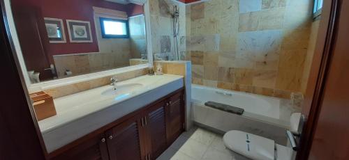 een badkamer met een wastafel, een toilet en een spiegel bij Villa Adais in Playa Blanca