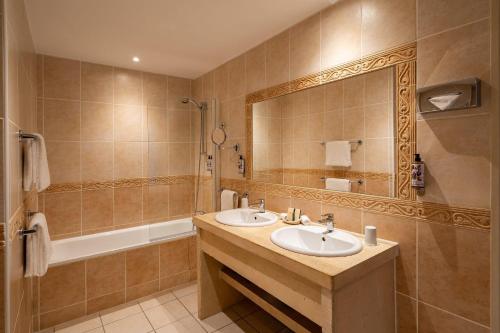 a bathroom with two sinks and a mirror and a tub at Chateau des Ducs de Joyeuse, BW Signature Collection in Couiza