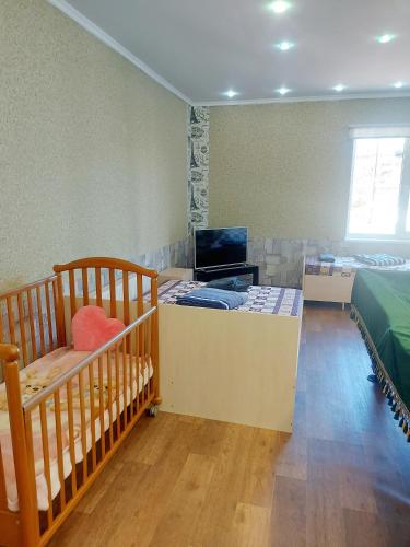 a room with a crib and a bed and a television at Отель Семейный in Zatoka