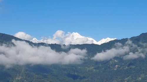 a mountain covered in clouds with snow capped mountains at Hotel Rashak in Gangtok