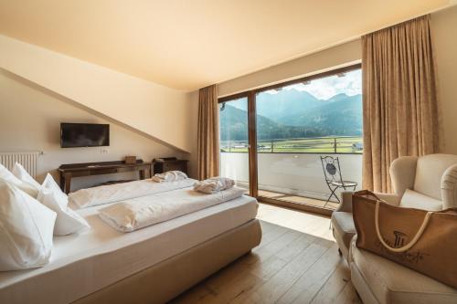 een hotelkamer met een bed en een groot raam bij Historic Hotel Alte Goste in Valdaora