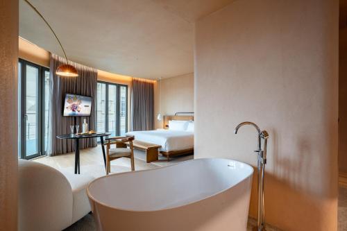 a hotel room with a tub and a bedroom at Akeah Porto Centro in Porto