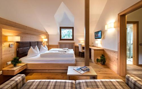 a hotel room with a bed and a couch at Hotel Fil Da Mont in Selva di Val Gardena
