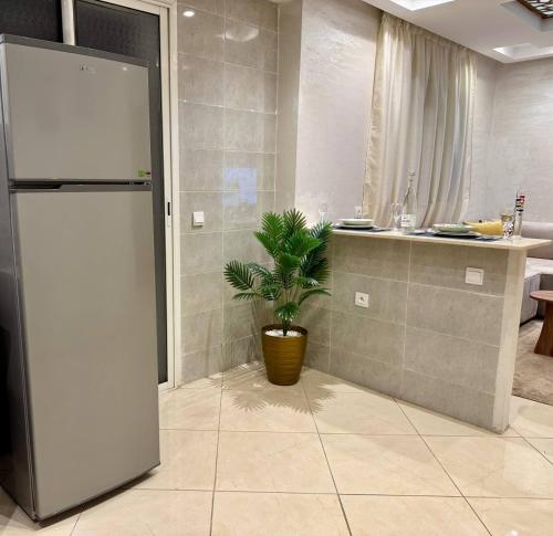 a kitchen with a refrigerator and a potted plant at Comfort & Style Apartment in Kenitra
