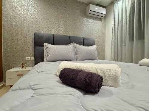 a bedroom with a large white bed with a gray headboard at Comfort & Style Apartment in Kenitra