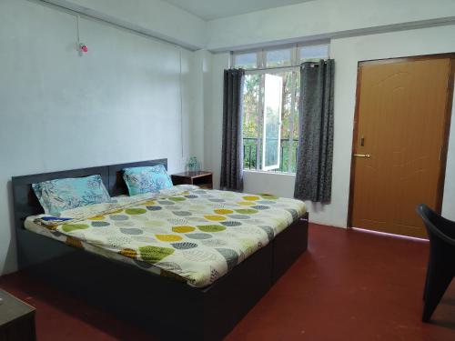 Un dormitorio con una cama en una habitación con ventana. en HOTEL Makarios, en Shillong