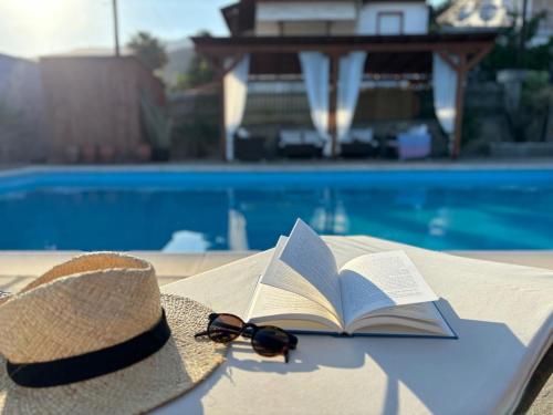 a hat and sunglasses and a book on a table by a pool at Cittadella Asprovalta 3BR - private pool in Asprovalta