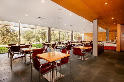 a restaurant with tables and chairs and windows at Axis Ponte de Lima Golf Resort Hotel in Ponte de Lima