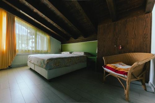 a bedroom with a bed and a chair and a window at Casa Laret 6-12 in Laax-Murschetg