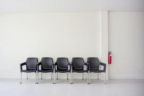 een rij zwarte stoelen in een witte kamer bij OYO 94903 Akasia Guesthouse in Perbaungan