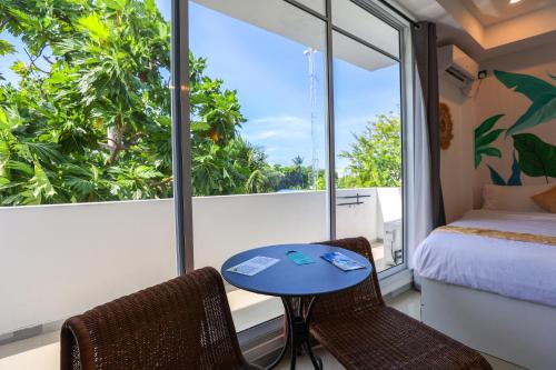 a room with a bed and a table and chairs at Sands Garden Hotel in Thoddoo