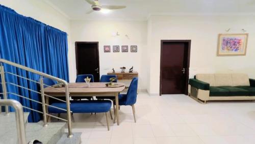 un salon avec une table et des chaises bleues dans l'établissement Villa In Precinct 10a Bahria Town Karachi, à Karachi