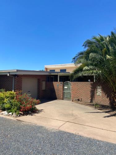 a brick house with a gate and a palm tree at Yarrawonga Holiday Home in Yarrawonga