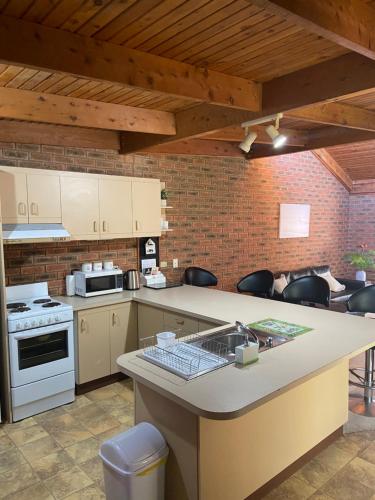 a kitchen with white appliances and a brick wall at Yarrawonga Holiday Home in Yarrawonga