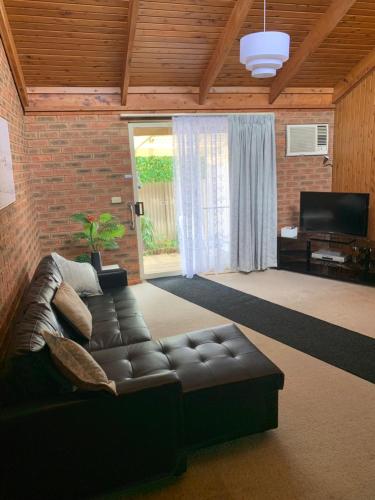 a living room with a leather couch and a television at Yarrawonga Holiday Home in Yarrawonga