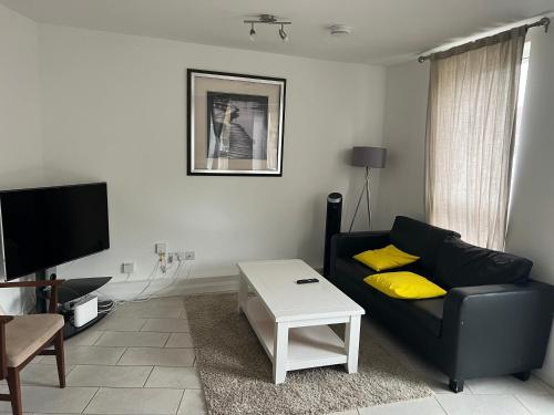 a living room with a black couch and yellow pillows at Cosy double room in Canada Water in London