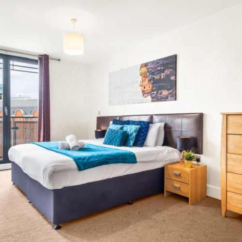 una camera da letto con un letto grande con cuscini blu di Stylish Apartment - Private Parking - Balcony - Chinatown - 49Arc a Birmingham