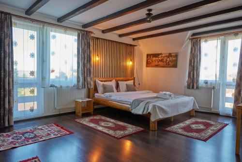 ein Schlafzimmer mit einem Bett in einem Zimmer mit Fenstern in der Unterkunft Casa Elder Villa in Bran