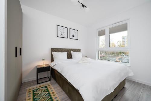 una camera da letto bianca con un letto grande e una finestra di Widzewska Prime Apartments by BookingHost a Łódź