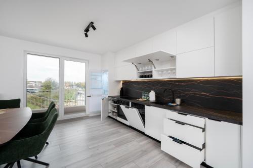 una cucina con mobili bianchi, tavolo e sedie di Widzewska Prime Apartments by BookingHost a Łódź