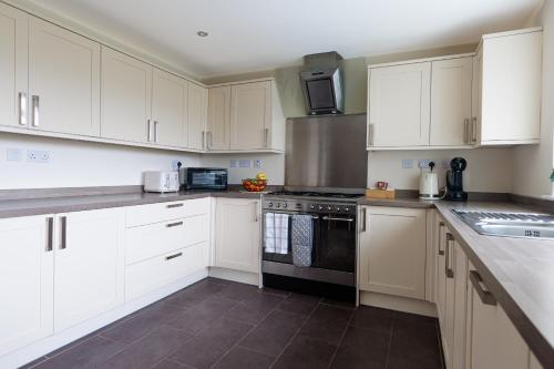 a kitchen with white cabinets and a stove top oven at 5BR Home, Sleeps 14, Free Parking, Comfortable LE3 Stay in Leicester