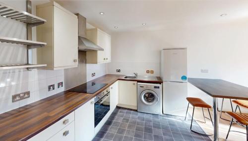 a kitchen with white cabinets and a washer and dryer at Three Bed Flat on Shakespeare St Sleeps up to 6 in Nottingham