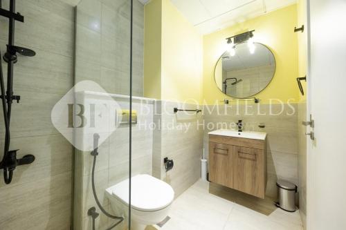 un baño con inodoro y espejo en Bloomfields Snug Stu Oasis Masdar, en Al Wathbah