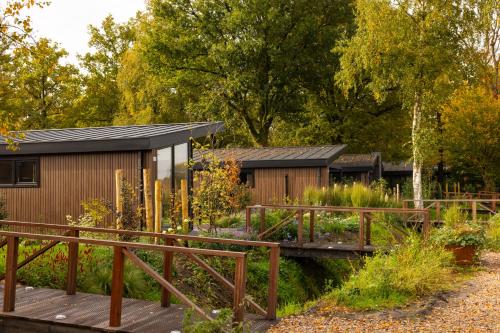 a garden with a wooden bridge and a building at De Leughte in Renswoude