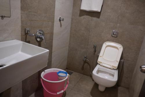 a bathroom with a sink and a toilet and a trash can at Hotel Royal Residency in Umele