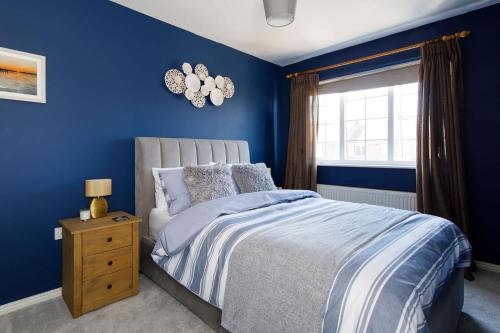 a blue bedroom with a bed and a window at Family Seaside Escape - 5 Mins to Beach in Earnley