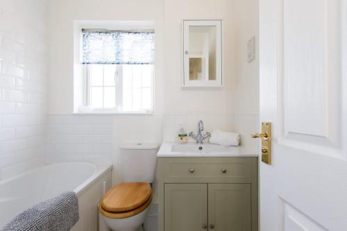 a white bathroom with a toilet and a sink at Family Seaside Escape - 5 Mins to Beach in Earnley