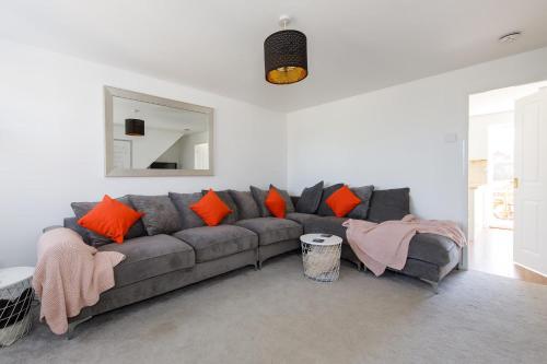 a living room with a gray couch with orange pillows at Family Seaside Escape - 5 Mins to Beach in Earnley