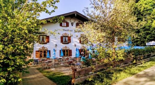 a white building with tables and chairs in front of it at Hotel Gasthaus Aujäger in Egling