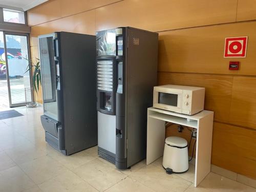 een kamer met een koelkast en een magnetron bij Avenida Gijón Centro in Gijón