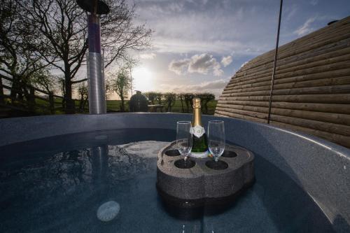 a bottle of champagne and glasses on a table next to a swimming pool at The Hygge Out - Glamping Site in North Yorkshire in Ebberston