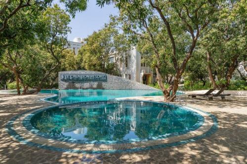 a swimming pool in a park with trees at Le Casa Lion Resort A Premium Resort In Sasan Gir in Sasan Gir