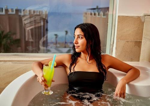 Eine Frau in der Badewanne mit einem Getränk in der Unterkunft Juliana Golden Beach Resort in Hurghada