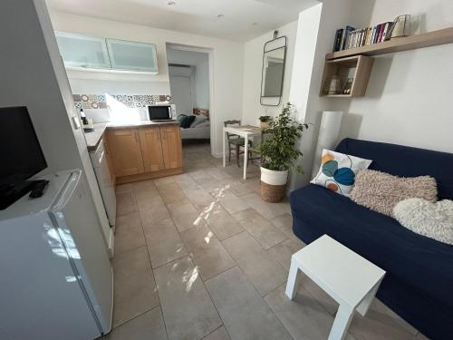 een woonkamer met een blauwe bank en een keuken bij Two rooms with 30 m2 garden in villa in Cagnes-sur-Mer