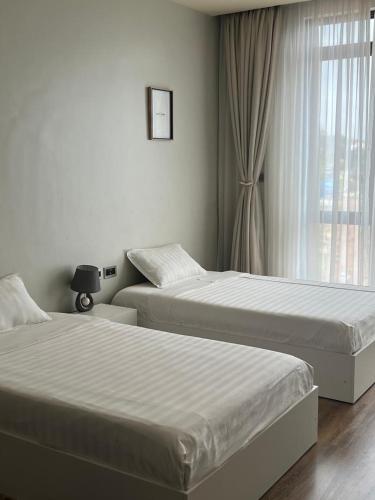 two beds in a hotel room with a window at The Happy Nest in Kampala