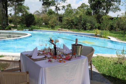 a table with a white table cloth next to a swimming pool at Pristine Mara Bay Lodge in Masai Mara