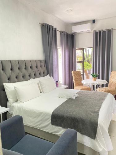 a bedroom with a large bed and two chairs at 63 Lodging Villa in Rustenburg