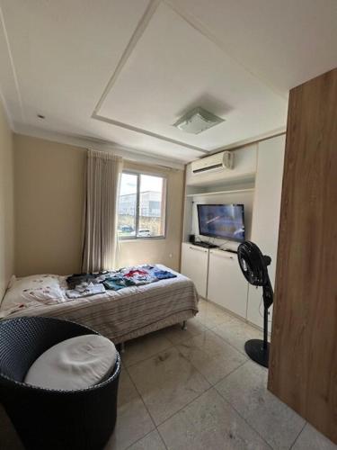a bedroom with a bed and a chair and a television at COP 30 aconchego e conforto in Ananindeua