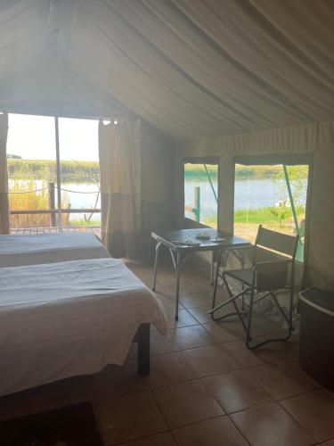 a bedroom with a bed and a table and chairs at Proudly Okavango self-catering Burnside in Shakawe
