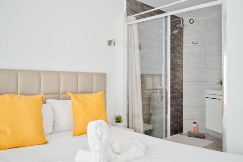 a bedroom with a white bed with yellow pillows and a shower at Las Tortugas Bungalow Beach in Arona