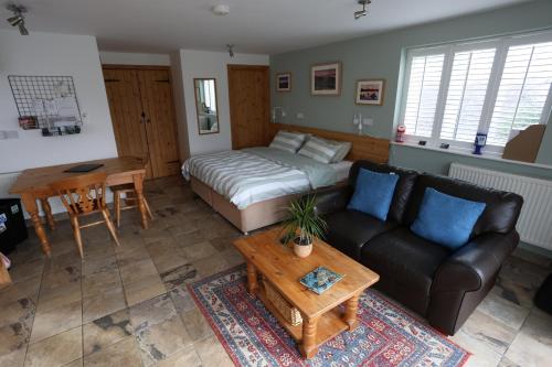 a living room with a bed and a couch and a table at Lynton Lodge Studios in Keswick