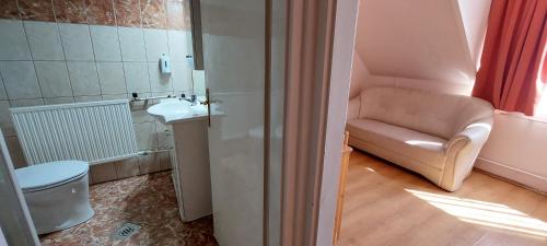 Un pequeño baño con lavabo y sofá. en Thermál Apartmanház, en Komárom