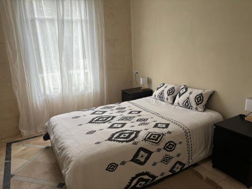 une chambre avec un lit avec une couverture noire et blanche dans l'établissement Maison Colibri, à Salies-de-Béarn