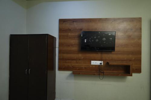 a wooden wall with a tv and a cabinet at Hotel Aasopalav in Ahmedabad