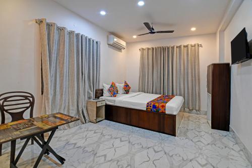 a bedroom with a bed and a table and a television at FabHotel AI Howrah in Kolkata
